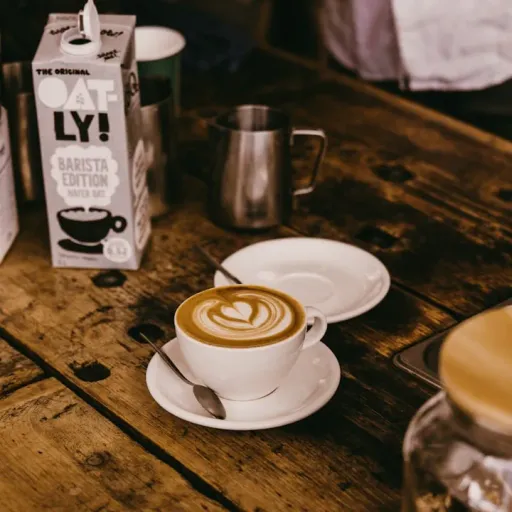 a cappuccino sits on a table next to two boxes of coffee
